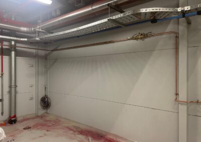 Copper and metal plumbing pipes installed along the walls and ceiling of a utility room.