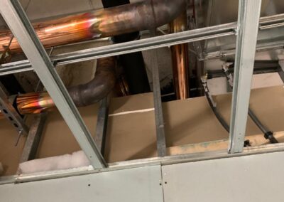 Exposed copper plumbing pipes with joints above partially installed ceiling framework.