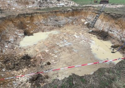 Excavated muddy pit with standing water, ladder for access, and construction tape barrier. - Fosker Plumbing Western Sydney
