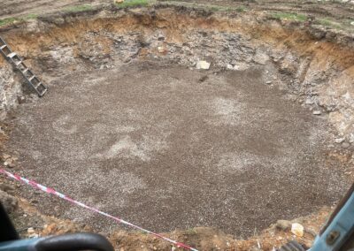 Excavated circular pit with gravel base, surrounded by soil and a ladder on the side. - Fosker Plumbing Western Sydney